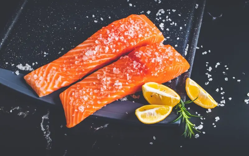 Raw salmon fillets with lemon wedges